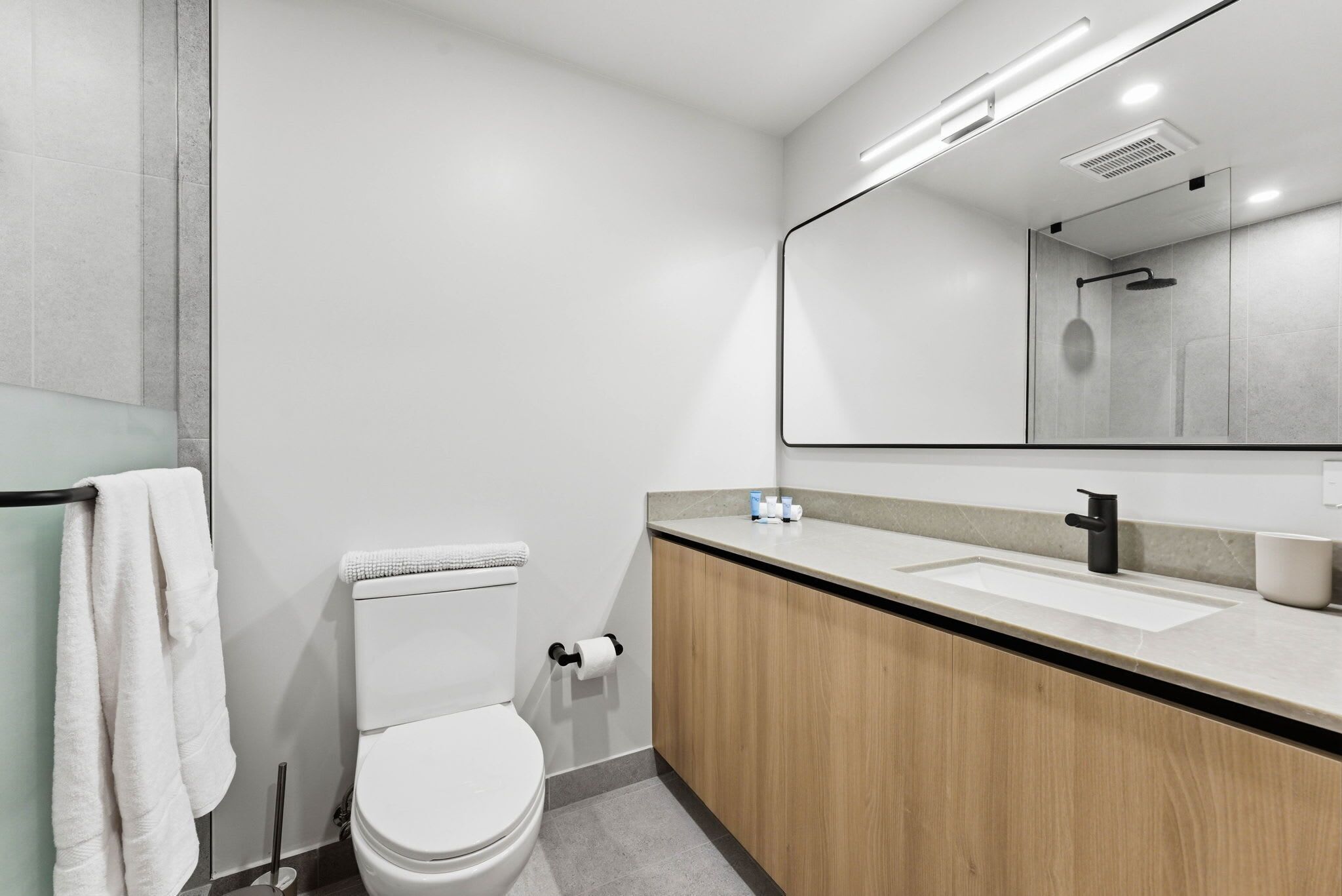 A modern bathroom with a toilet, sink, and mirror.