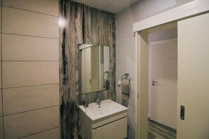 A bathroom with a white sink, a mirror, and a towel rack. - House of the Brazilian (Arco da Calheta)