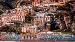 A coastal town with colorful buildings, a beach with blue umbrellas, and a rocky cliff. - Room-charming Panoramic Suite in the Cen (Positano)