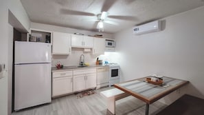 A compact kitchen with white cabinets, a refrigerator, a microwave, an oven, and a ceiling fan. -  SOLACE  Gorgeous 2-bedroom villa with AC (Bolands , Saint Mary)