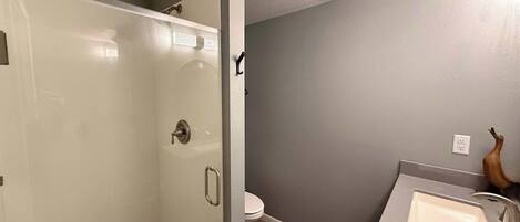 A bathroom with a shower, toilet, and sink.