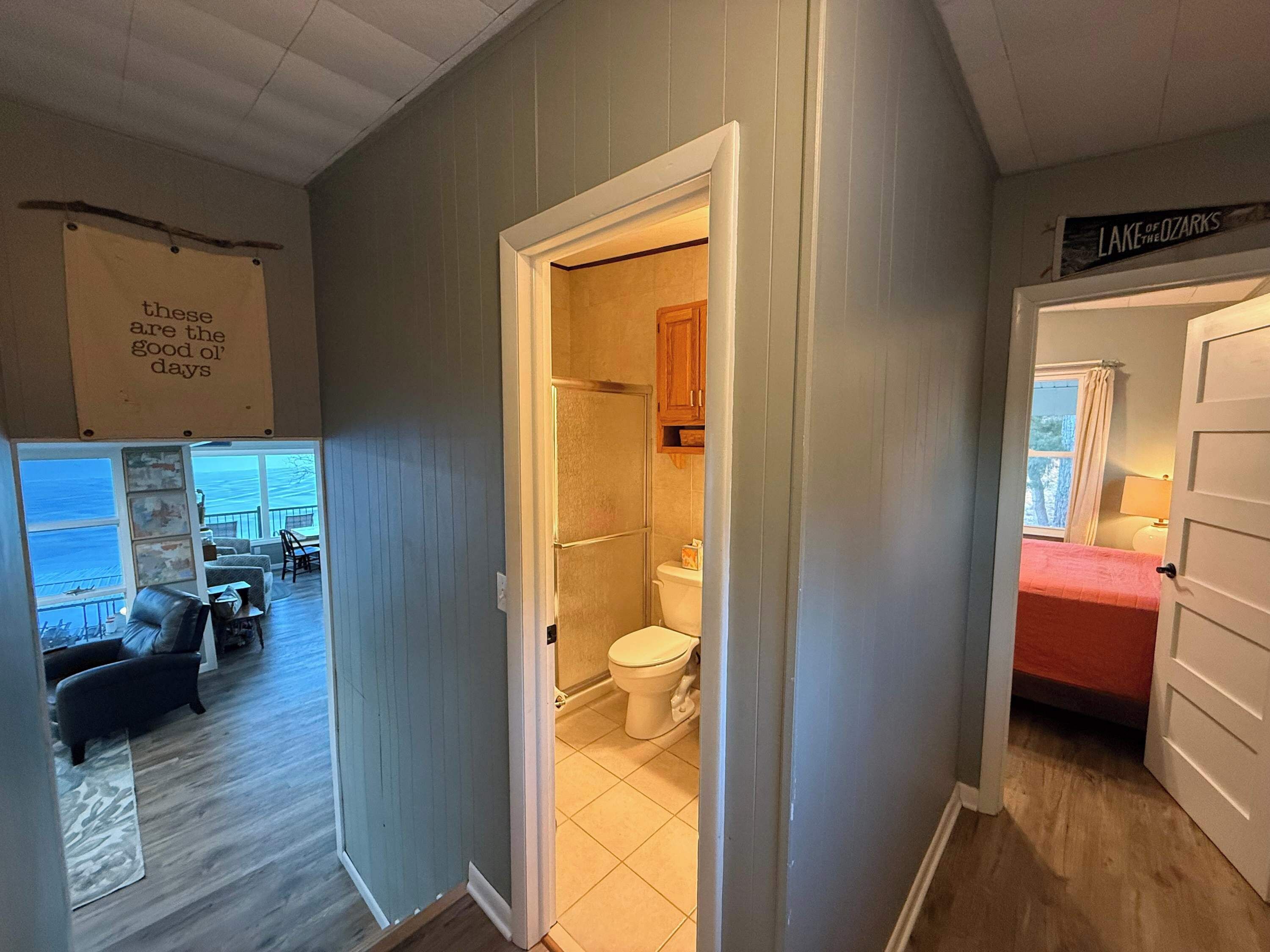 A hallway leading to a bathroom with a toilet, a shower, and a visible window.