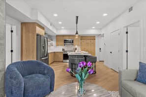 Una cocina moderna con armarios de madera, una isla central y un comedor con sillas.