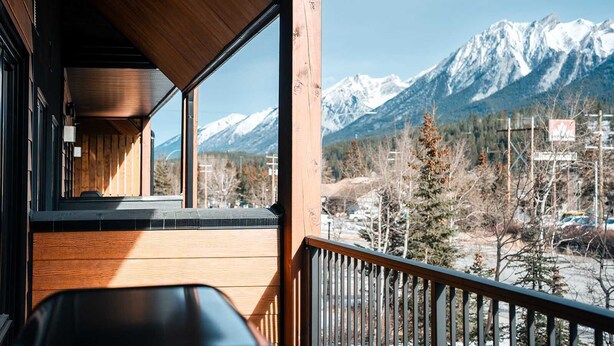 A wooden balcony with a view of snow-capped mountains.