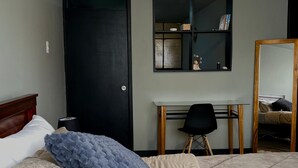 Una camera da letto con un letto, una scrivania e uno specchio.
