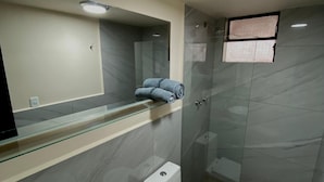 Un bagno moderno con cabina doccia in vetro, un water bianco e un lavandino bianco.
