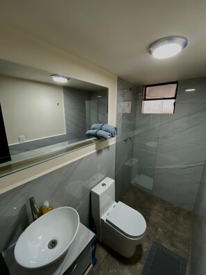 A modern bathroom with a glass shower enclosure, a white toilet, and a white sink. - Confortable Independen studio flat (Quito)