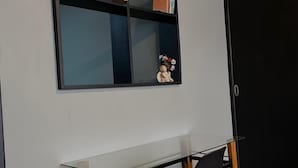 Una stanza con una scrivania in vetro, una sedia nera e una libreria nera addossata a una parete bianca.