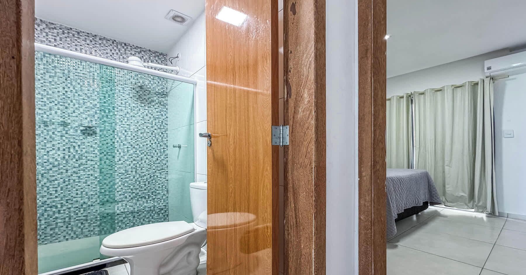 Un baño con cabina de ducha de vidrio, inodoro y puerta de madera.