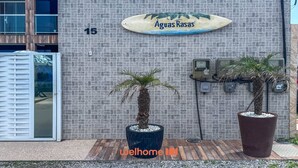 Un edificio con un cartel que dice 'Aguas Rasas' y el número '15' en la pared. Hay dos palmeras en macetas al frente.
