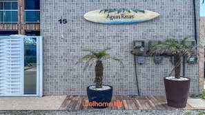 A building with a sign reading 'Aguas Rasas' and the number '15' on the wall. There are two potted palm trees in front.