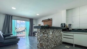 Una cocina moderna con salpicadero de azulejos, zona de comedor con sofá y vista a una piscina a través de un ventanal.