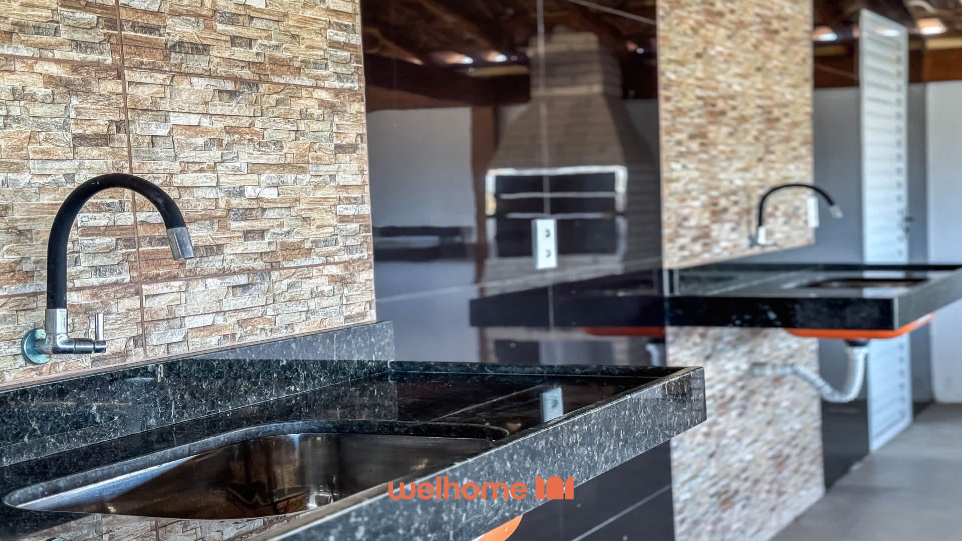 Eine moderne Küche mit Granit-Arbeitsplatten, einer Edelstahl-Spüle und einer Rückwand mit Steinoptik.