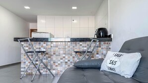 A modern kitchen with a tiled backsplash, a coffee machine, and a bar stool. - Apto Arraial do Cabo c/ Piscina e Bilhar (Arraial do Cabo)