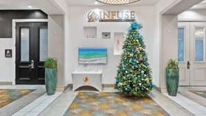 Un hall d’entrée décoré d’un sapin de Noël, un comptoir d’accueil et une enseigne indiquant « INFUSE IV HYDRATION & WELLNESS ».