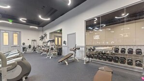 Une salle de sport équipée de machines de cardio, de bancs de musculation et d’un mur rempli d’haltères.