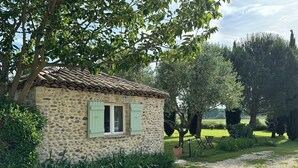 Un rustico cottage in pietra con tetto di tegole, immerso nel verde e circondato da alberi.