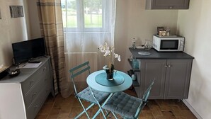 Un angolo cottura funzionale con forno a microonde, un pensile, una TV e un'area pranzo con tavolo e sedie.
