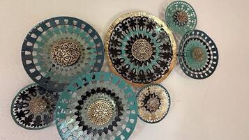 Une collection d’assiettes décoratives aux motifs complexes et aux centres métalliques, disposées sur un mur sobre.