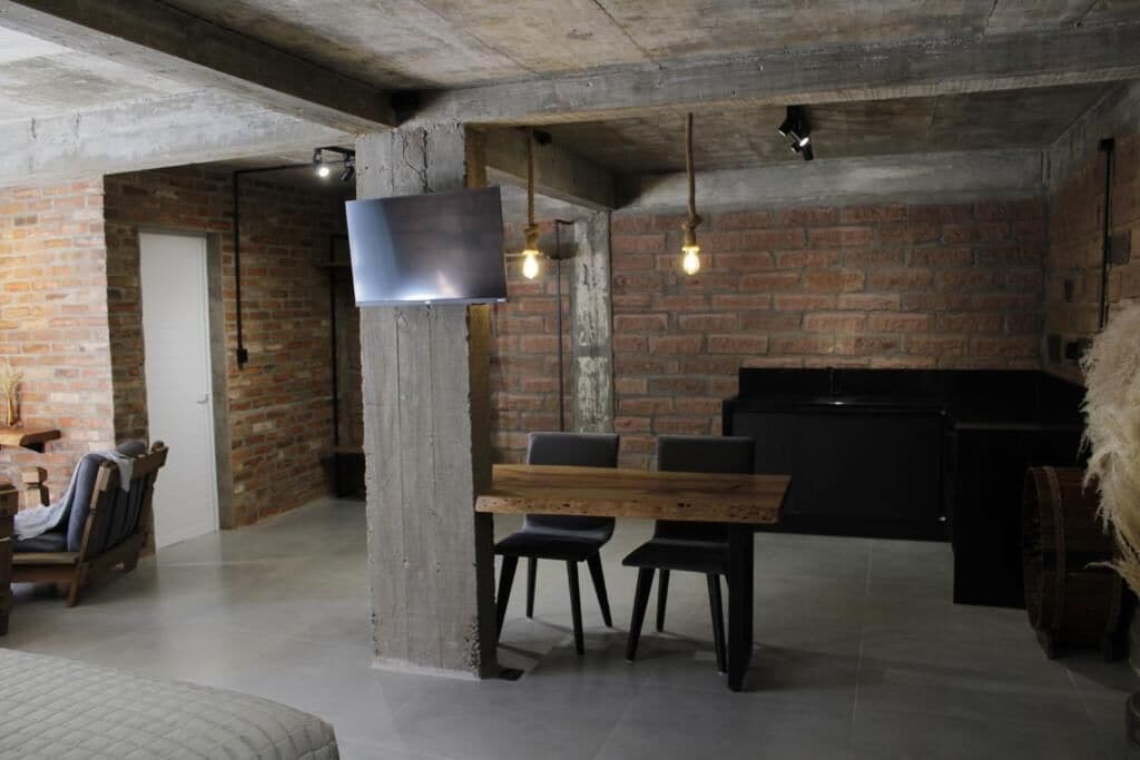 Une pièce spacieuse avec des murs en briques apparentes, une table à manger en bois et des chaises modernes.