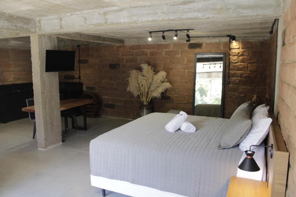 Een slaapkamer met een bed, een bureau, een stoel, een televisie en een spiegel.