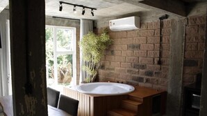 Ein modernes Badezimmer mit einer Holzbadewanne, einer Ziegelwand und einem Fenster.