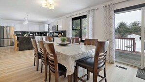 Una cucina moderna con mobili bianchi, un tavolo da pranzo con sedie e vista su una terrazza attraverso una grande finestra.