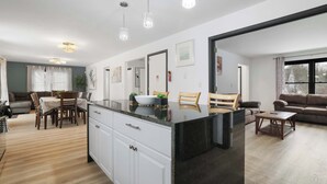 Una cucina moderna con mobili bianchi, un piano di lavoro nero e illuminazione a sospensione.