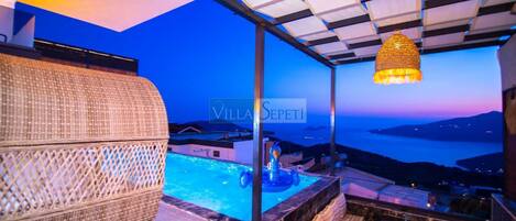 Un balcón con piscina, muebles de mimbre y una lámpara colgante.