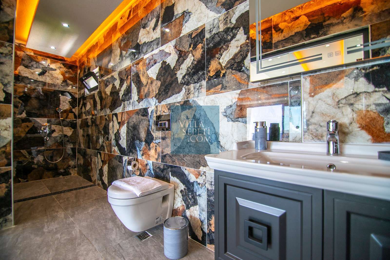 A bathroom with a stone wall, a toilet, a sink, and a shower.