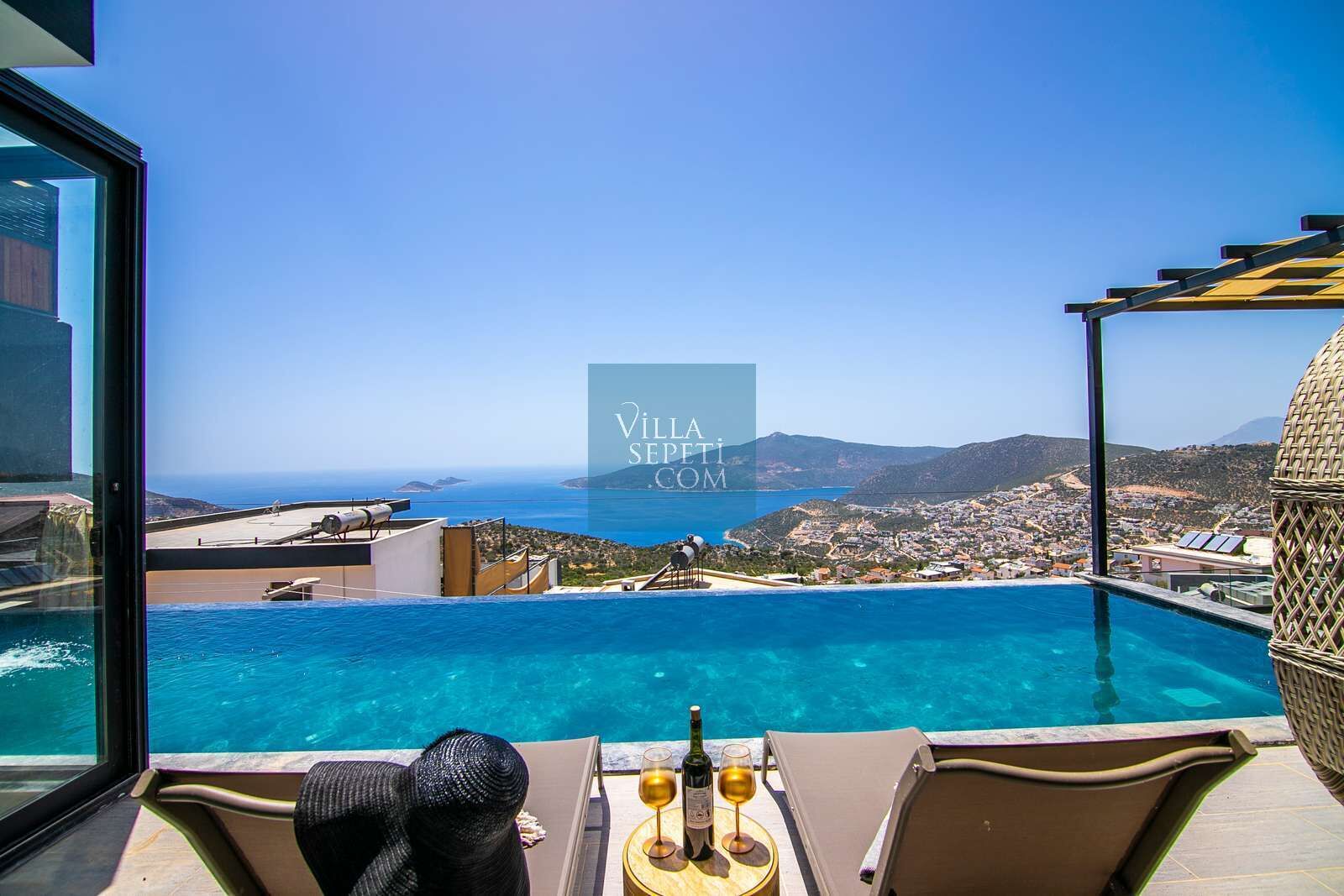 A poolside view with a clear view of the sea and a town in the background.