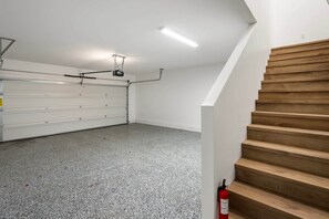 Een garage met een houten trap, een garagedeur en een brandblusser.