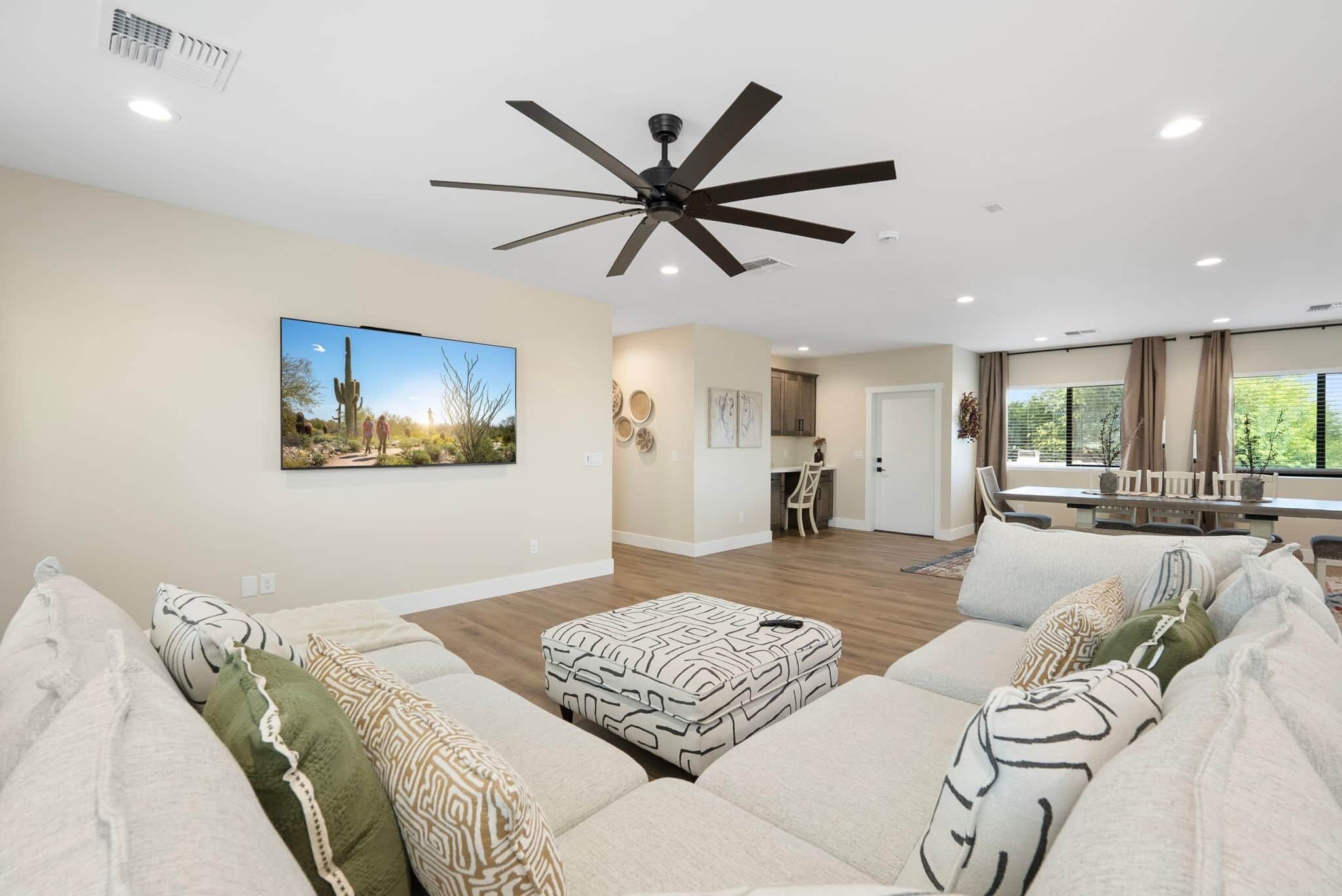 A living room with a sofa, ottoman, ceiling fan, and a painting on the wall.