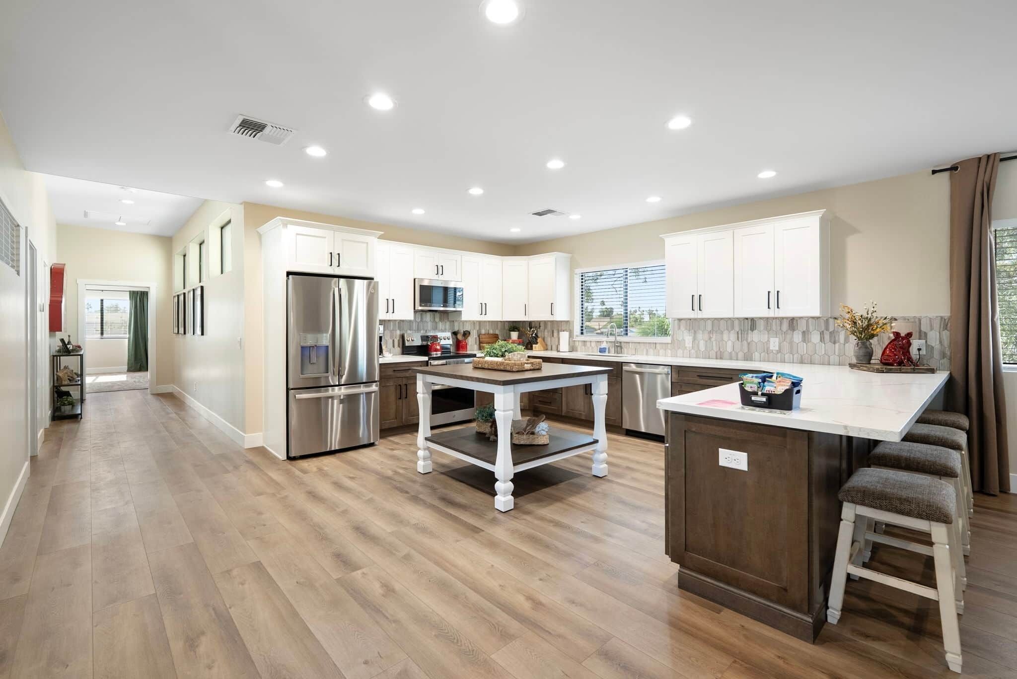 Cocina moderna con armarios blancos, electrodomésticos de acero inoxidable, una isla central y vistas al exterior.
