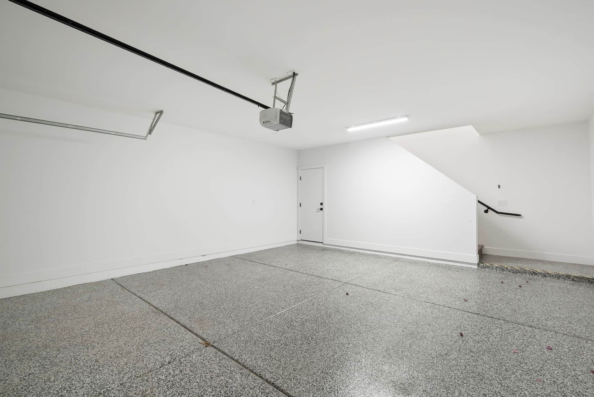 Ein geräumiger, leerer Raum mit schrägem Dach, einem an der Decke befestigten Projektor und einer Tür an der rechten Wand.