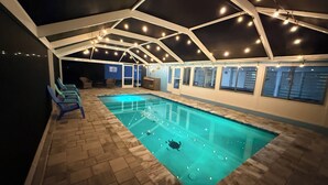 Piscina interior com superfície de água cristalina, rodeada por chão em azulejo e estrutura de teto branca.