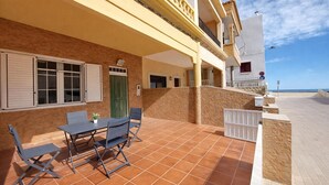 A patio with a table and chairs, a green door, and a view of the sea. - Lovely home in Sueca with WiFi (Sueca)