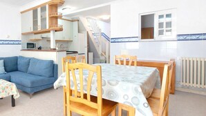 A compact living space with a kitchenette, a dining area, and a staircase leading to an upper level. - Lovely home in Sueca with WiFi (Sueca)
