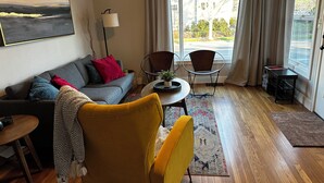 A modern living room with a sofa, armchairs, a coffee table, and a dining table.