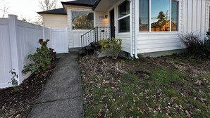 A single-story house with a front porch, a visible address number, and a small front yard with a pathway leading to the entrance.