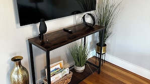 A wooden TV stand with a flat-screen TV, a remote, and decorative items.