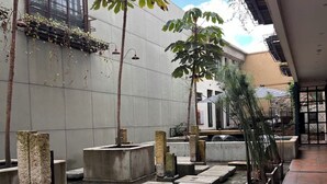 Un patio con fuente de agua, macetas de piedra y fachada de edificio.
