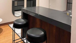Una cocina moderna con una isla central, taburetes negros y luces colgantes.