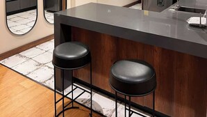 Una cocina moderna con una isla central, dos taburetes de bar y un espejo grande.