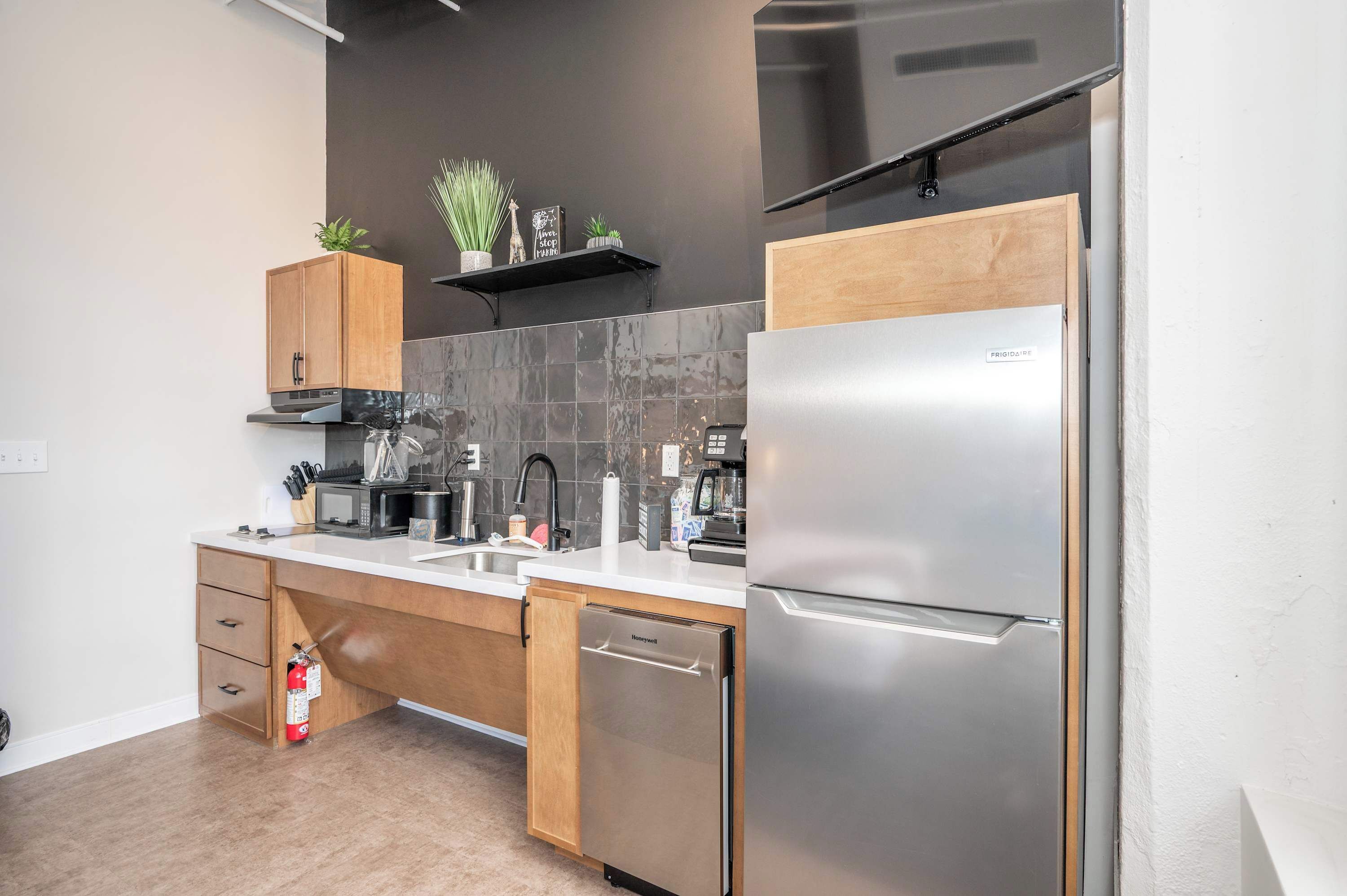 A modern kitchen with a built-in dishwasher, stainless steel refrigerator, and a microwave.