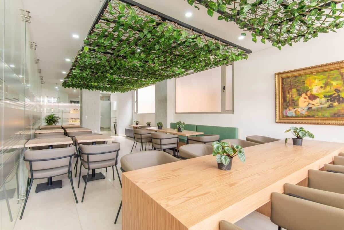 A modern conference room with a long wooden table, several chairs, and a green plant hanging from the ceiling.