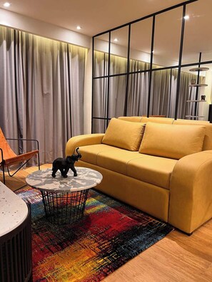 Un salon moderne avec un canapé jaune, une table basse ronde et un tapis coloré.
