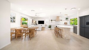 A modern kitchen with a central island, built-in appliances, and a dining area with wooden furniture. - Solara Escape Mooloolaba, Pool + Dog-Friendly Home (Mooloolaba Region)