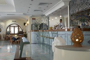 A bar area with a bartender, a decorative pineapple, and a patterned wall. - Hotel Tritone Resort AND SPA (Forio)