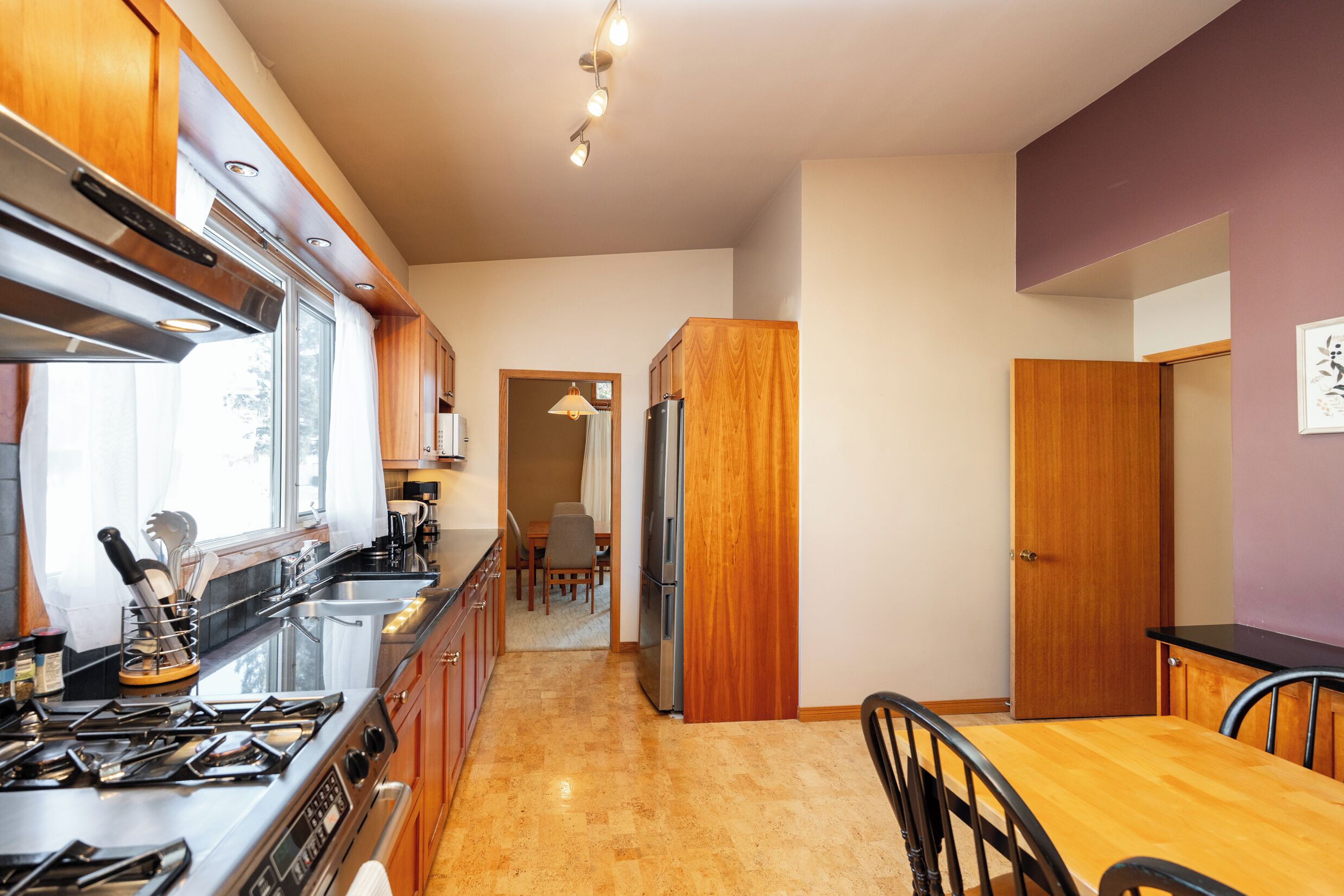 A modern kitchen with wooden cabinets, a stainless steel stove, and a refrigerator.